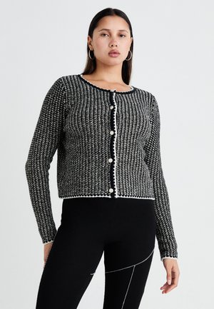 Black and white textured cardigan with a round neckline, button front, and contrasting trim. Long sleeves, cropped design, and decorative buttons.