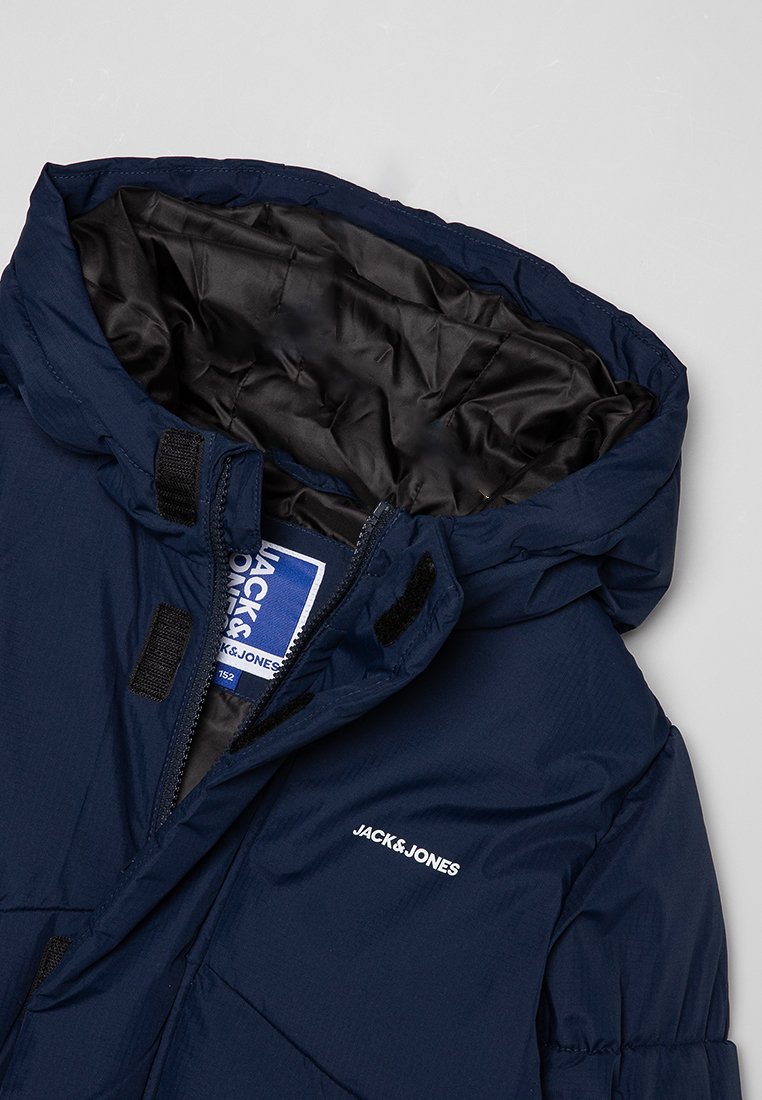 Granatowa, ocieplana kurtka zimowa Jack & Jones z kapturem, zamkiem błyskawicznym i zapięciem na rzepy, z widoczną czarną, pikowaną podszewką.