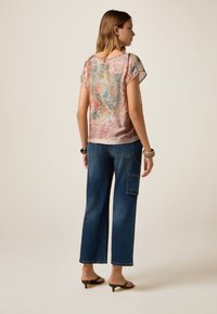 Lichtgewicht, gestreepte blouse met bloemdessin in roze en blauw, gecombineerd met ontspannen blauwe denim jeans met een zijzak.