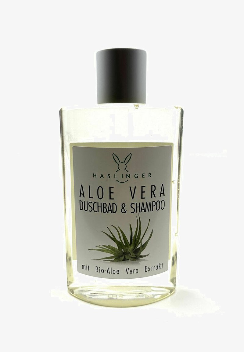 Durchsichtige rechteckige Flasche mit schwarzem Deckel, beschriftet "Aloe Vera Duschbad & Shampoo." Enthält Flüssigkeit mit einer Aloe-Pflanze Grafik und Text.