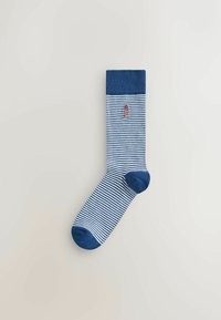 Une chaussette rayée bleue et blanche avec un bout, un talon et un revers bleus unis, avec un petit phare rouge et blanc brodé près du haut.