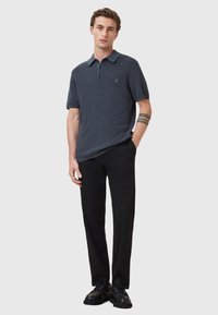 Granatowa, teksturowana koszulka polo z krótkimi rękawami, z zapięciem na dwa guziki, w połączeniu z czarnymi spodniami i czarnymi butami sznurowanymi. Minimalistyczny design.