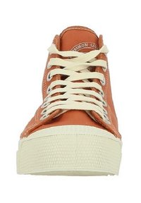 Basket orange montante avec lacets blancs, semelle en caoutchouc texturée et patch logo rond à la cheville, avec des détails de couture contrastants.