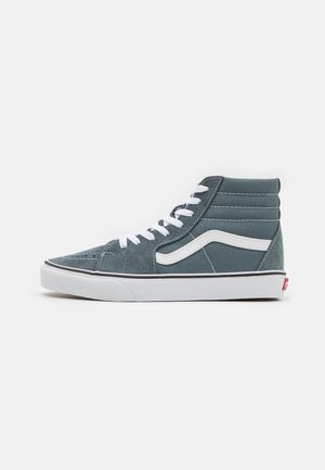 Højtop-sneaker i afdæmpet blå med hvid bølgestribe, hvide snørebånd og hvid gummisål mod hvid baggrund.