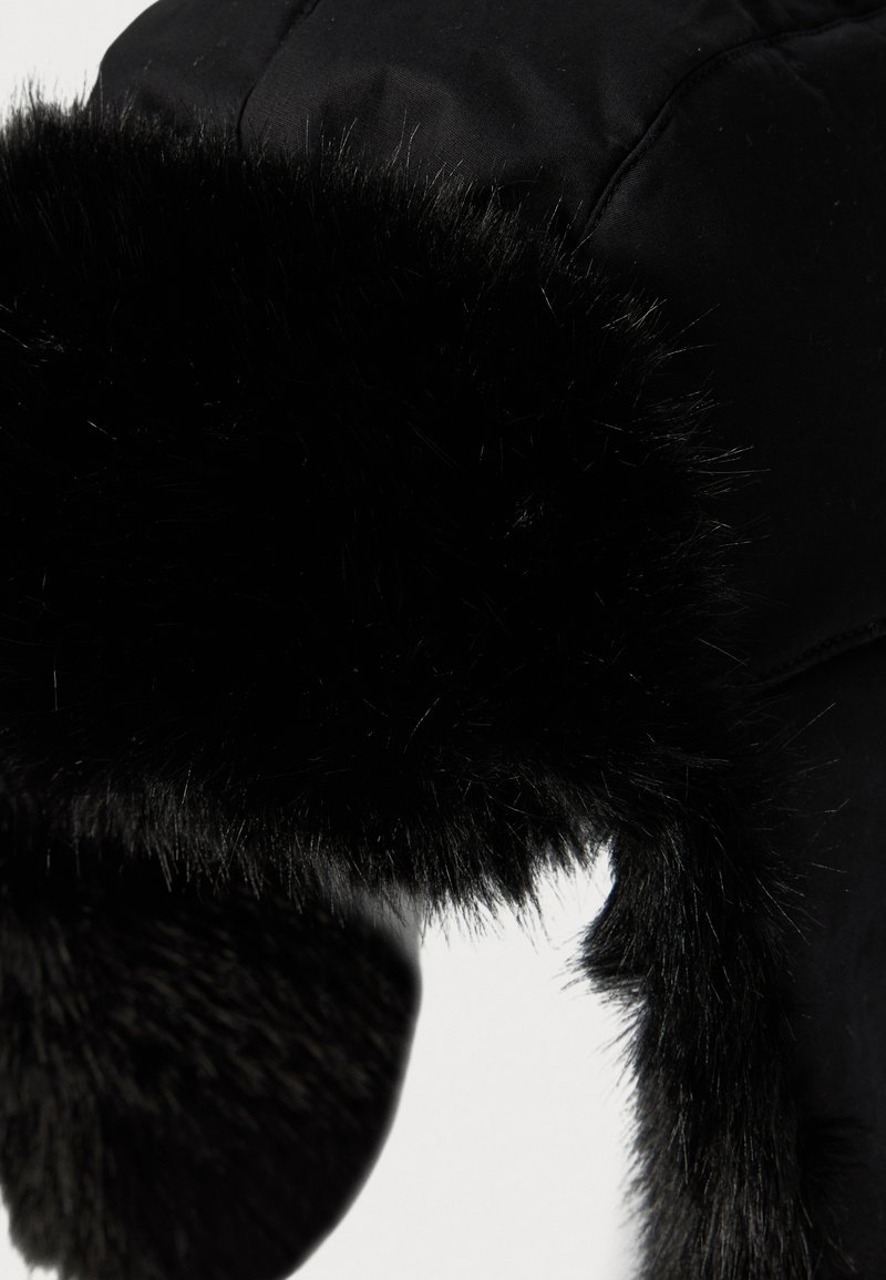 Cappello invernale nero con morbido e spesso rivestimento in pelliccia sintetica e alette per le orecchie su uno sfondo bianco.