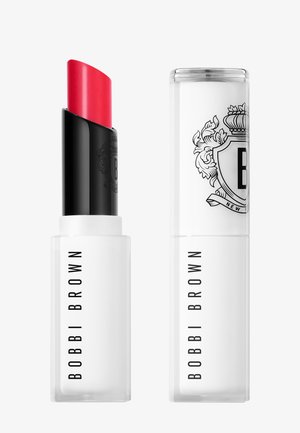 Rouge à lèvres rouge vif dans un étui Bobbi Brown blanc et noir, présenté avec le capuchon en place et retiré, sur un fond blanc uni.