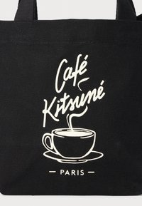 Svart totebag med hvite trykte grafikker av en kaffekopp med damp, teksten "Café Kitsuné" og "PARIS" i en moderne font.