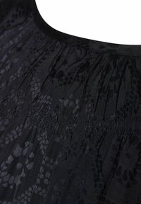Juodas audinys su gėlių raštu, kurio atspalviai skiriasi, minkšta tekstūra, susirinkusi iškirptė ir elastingi siūlių detalės.