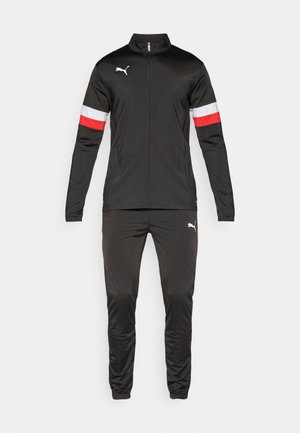 Chándal negro con chaqueta con cremallera y franjas rojas y blancas en las mangas, combinado con pantalones a juego. Hecho de un material deportivo y suave.