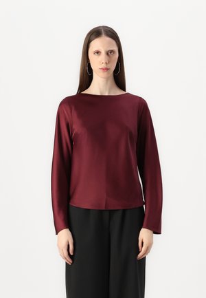 Burgundy long-sleeve top in smooth fabric, featuring a round neckline and relaxed fit, paired with black trousers. Simple design, no patterns.