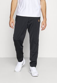 Pantalones atléticos negros con una textura suave y un diseño ajustado. Presentan bolsillos laterales sutiles y un logo de marca en color contrastante.