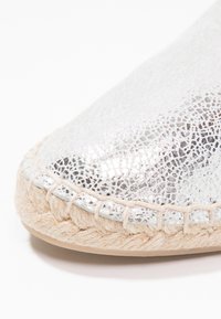 Silver leather espadrille with a cracked texture, flat jute sole, and stitched trim detailing. Rounded toe and smooth finish.
