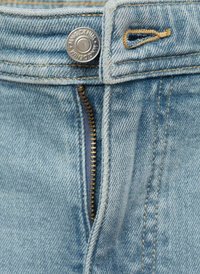 Lichtblauwe denim jeans hebben een metalen knoop, ritsdetails en praktische stiksels. De stof heeft een zachte textuur met subtiele tonale variaties.