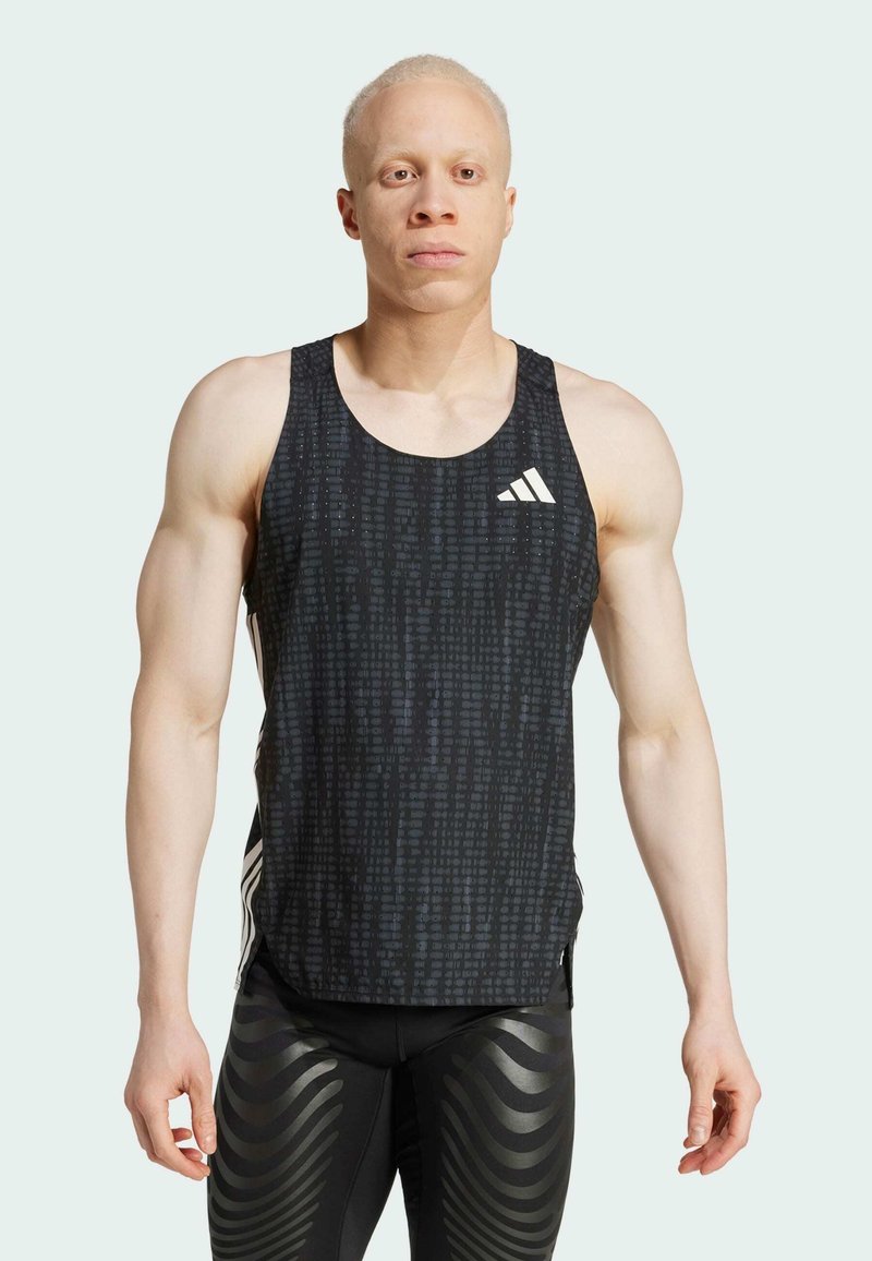 Czarny sportowy top na ramiączkach z teksturowanym wzorem, z okrągłym dekoltem i białym logo Adidasa po lewej stronie klatki piersiowej. W zestawie z czarnymi legginsami we wzór.