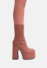 Stivali alla caviglia in pelle marrone con piattaforma, design fino al ginocchio, fascia con fibbia e tacco spesso, caratterizzati da una superficie liscia e una silhouette elegante.