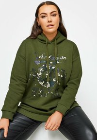 Olivgrön huvtröja med ett fronttryck som har färgglad text och mönster, känguruficka och dragsko i huvan. Ribbad mudd vid ärmar och nederkant.