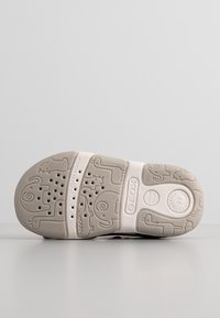 Semelle d'une chaussure Geox pour enfant avec des motifs en forme d'animaux, des trous de ventilation et les étiquettes "Flexy System" et "Softly Cushioned".