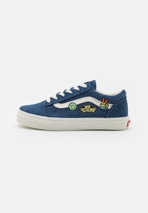 Blå denim lavtophælte sneakers med hvide snørebånd, der har broderede patches af smiley og fredstegn på siderne og en hvid gummisål.