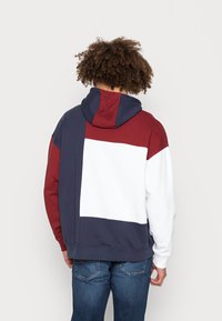 Kapuzensweatshirt mit einem Farbschema in Marineblau, Kastanienrot und Weiß. Mit einer weichen Textur sowie gerippten Bündchen und Saum.
