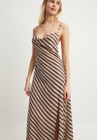 Brown and cream striped maxi dress with thin straps, a cowl neckline, and a side slit. Smooth fabric with a flowing silhouette.