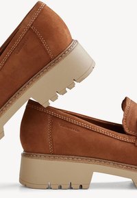 Mocassini in suede marrone con tacco a blocco, caratterizzati da un dettaglio cucito e una suola in gomma. Marchio visibile sul lato.