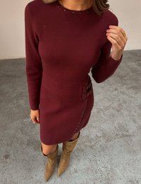 Bordowa sukienka dzianinowa z długimi rękawami, okrągłym dekoltem ozdobionym ćwiekami, bocznym zapięciem na guziki i efektownymi akcentami w postaci klamerek.