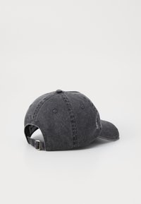 Căciulă din denim negru cu o margine curbată, curea ajustabilă la spate și o suprafață texturată. Prezintă detalii de coasere și găuri de ventilație.