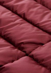 Bordeaux gekwilt stof met gestikte delen, met een gladde, glanzende textuur en gevoerde vulling voor warmte en comfort.