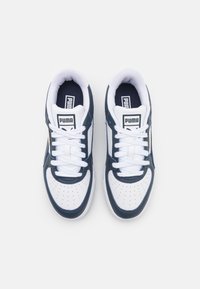 Navyblauwe en witte sneakers met geperforeerde neuskap, platte veters, gevoerde kraag en logo op de tong. Heeft een glad bovenwerk van synthetisch materiaal.