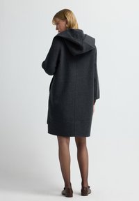 Darks grå hættetrøje lavet af blød uldblanding, med en afslappet silhuet, dybe sidelommer og et design der når til midten af låret.