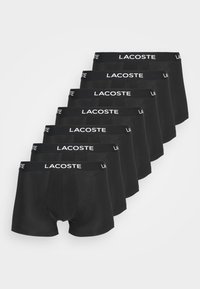Čierne boxerky usporiadané v rade, vyrobené z mäkkého a elastického materiálu, s bielym logom "LACOSTE" na páse.