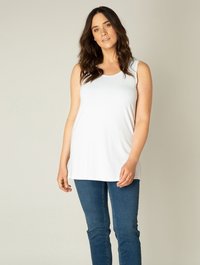 Witte mouwloze top met een ronde hals, gemaakt van zachte stof. Gecombineerd met blauwe spijkerbroeken. Soepele textuur, ontspannen pasvorm.