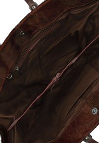 Intérieur de sac fourre-tout en brun, au toucher doux, avec une poche zippée et une poche plaquée ; doublure en tissu ; dispose de poignées en cuir assorties et de quincaillerie de fermeture.