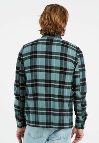 Flanellen shirt in teal met zwart-wit geruit patroon; met knoopsluiting aan de mouwen en klassieke kraag; zachte textuur en relaxte pasvorm.