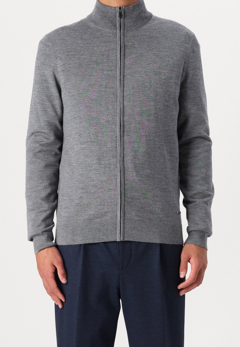 Šedá zipová mikina s vysokým límcem, pružnými manžetami a lemem. Měkký materiál, slim fit, minimalistický design. Žádné viditelné vzory ani emblémy.