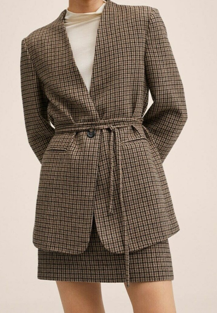Blazer marrón a cuadros con diseño envolvente, mangas largas y cierre de lazo, combinado con una falda a juego con patrón. Tela texturizada.