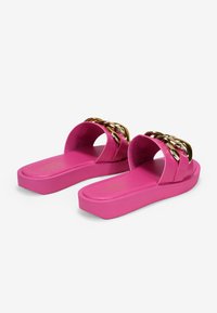 Pink platform slide sandals made of smooth material with a wide strap featuring a metallic gold chain detail.