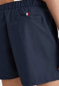 Bañadores de color navy con cintura elástica, bolsillos laterales y un bolsillo trasero que presenta una pequeña franja de acento en rojo, blanco y azul.