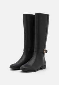 Botas negras hasta la rodilla hechas de cuero sintético suave, con un acento de hebilla dorada en una correa. La suela es plana y ligeramente texturizada.