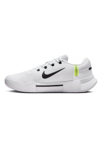 Baskets blanches avec une tige texturée, swoosh noir de Nike, étiquette d'accentuation verte et semelle en caoutchouc durable avec un motif en zigzag.