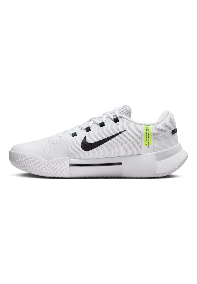 Baskets blanches avec une tige texturée, swoosh noir de Nike, étiquette d'accentuation verte et semelle en caoutchouc durable avec un motif en zigzag.