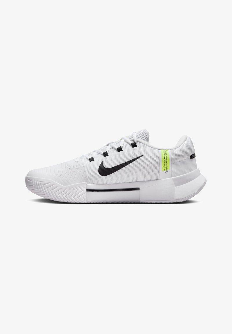 White athletic shoes with a textured upper, black Nike swoosh, green accent label, and durable rubber sole with a zigzag pattern.