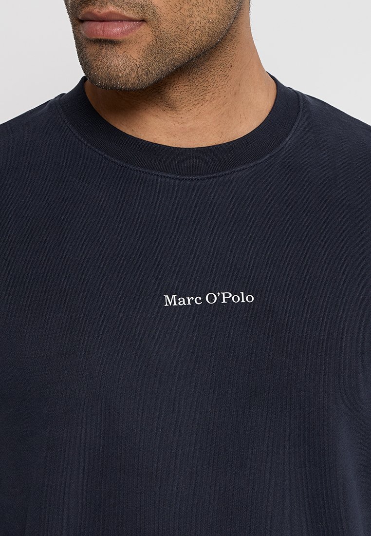 Sweatshirt bleu marine en coton, avec un col côtelé et un petit logo blanc "Marc O'Polo" sur le devant.