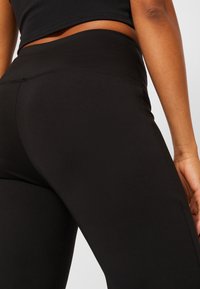 Černé legíny s hladkým, elastickým materiálem a designem s vysokým pasem. Mají minimální švy a elegantní, přiléhavý siluetu.