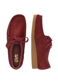 Punaiset mokka-kengät pehmeällä pinnalla, pyöreällä kärjellä, nauhakiristysmuotoilu, kontrastina oleva vaaleanruskea kumipohja ja ommellut yksityiskohdat yläosassa.