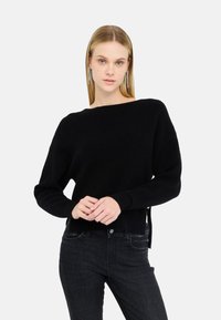 Maglione nero in maglia con scollo a barca, maniche lunghe e polsini a coste. Presenta spacco laterale all'orlo per una vestibilità comoda.