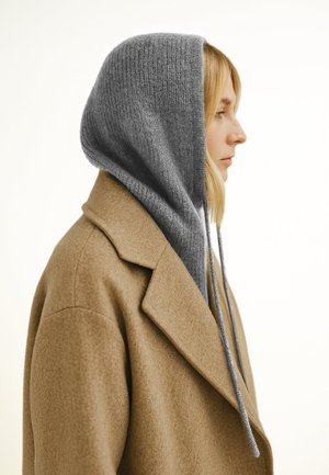 Brauner Wollmantel mit einer hellgrauen Strickkapuze. Die Kapuze hat eine gerippte Textur und lange Kordelzüge. Seitenansicht, glatte Kanten.