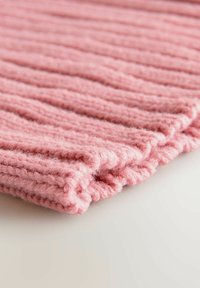 Gebreid roze stof met een geribbelde textuur, voorzien van zachte vezels en een golvende rand. De stof is gevouwen, waardoor de diepte en dikte worden benadrukt.