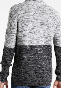 Sweter dziergany z gradientowym wzorem przechodzącym od jasnoszarego do czarnego. Posiada okrągły dekolt i długie rękawy z prążkowanymi mankietami.