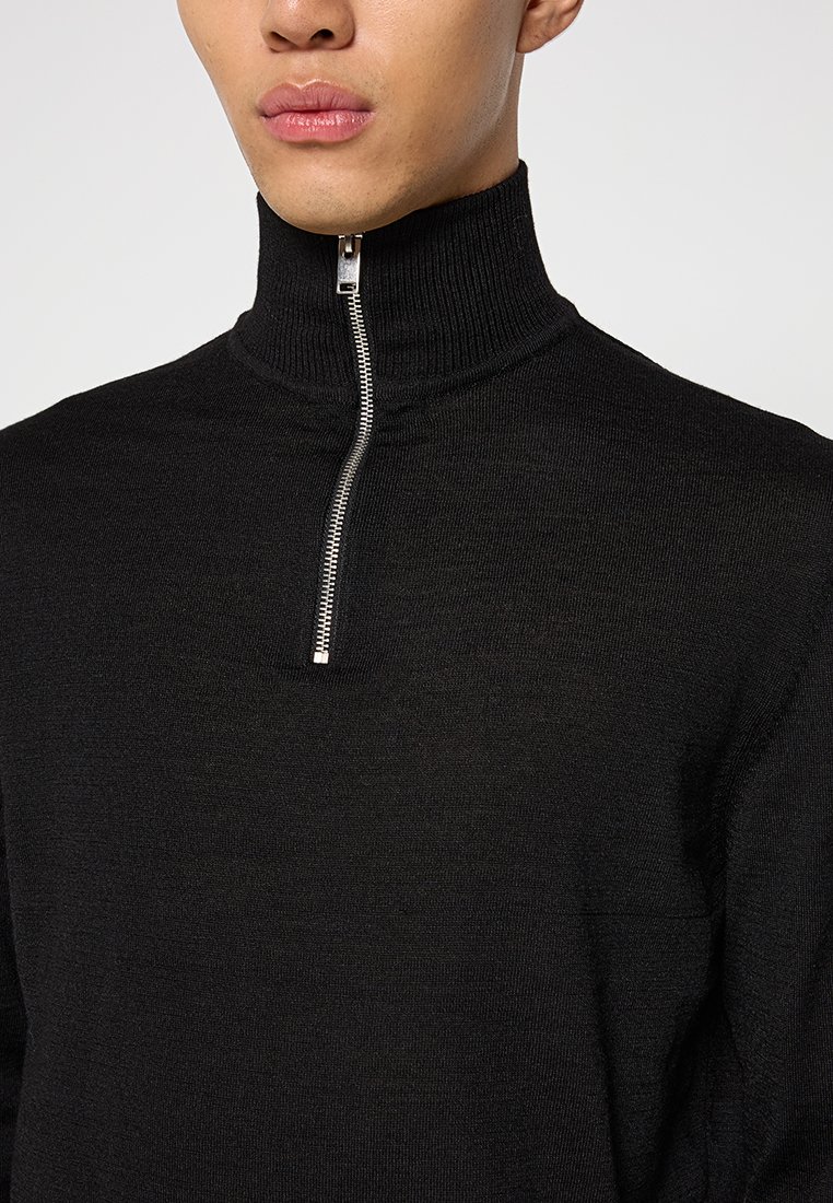 Pull noir à col montant en maille fine, doté d'une fermeture éclair argentée au niveau du col. Design simple avec une texture lisse.